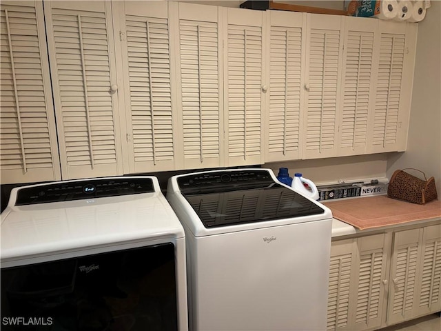 laundry area featuring washing machine and clothes dryer and cabinets