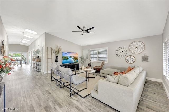 living room with a wealth of natural light, light hardwood / wood-style floors, ceiling fan, and vaulted ceiling