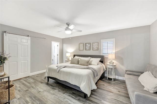 738 101st Ave N, Naples, FL 34108 - bedroom with wood finished floors, baseboards, a barn door, and a ceiling fan
