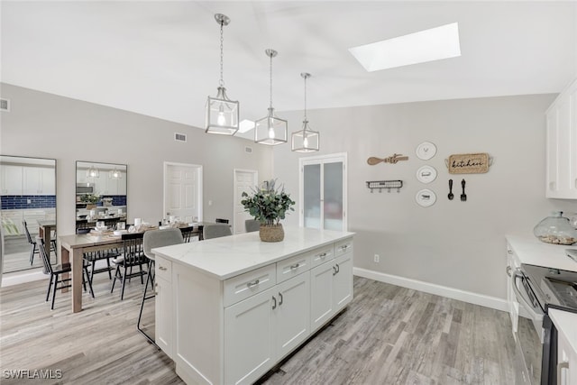738 101st Ave N, Naples, FL 34108 - kitchen featuring stainless steel appliances, a skylight, white cabinetry, a center island, and light wood-style floors
