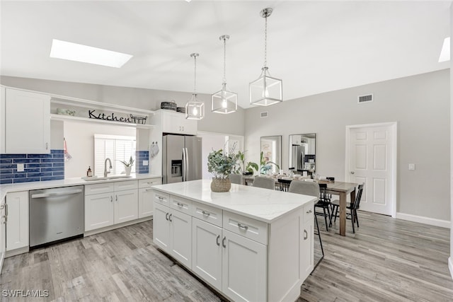 738 101st Ave N, Naples, FL 34108 - kitchen featuring stainless steel appliances, a sink, open shelves, a skylight, and light wood-style floors