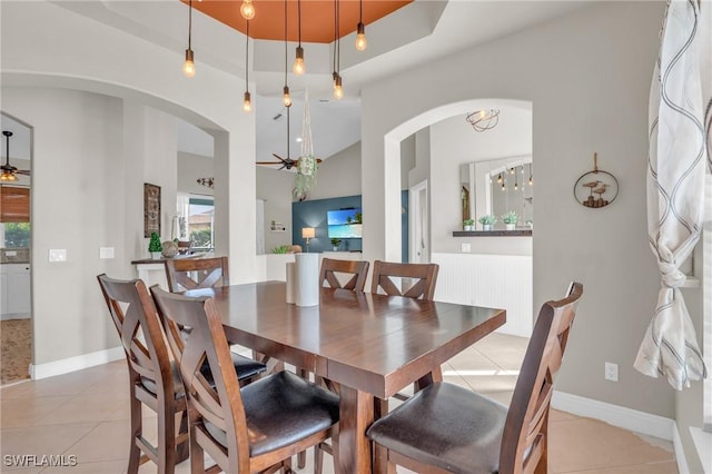 tiled dining room featuring ceiling fan and a tray ceiling