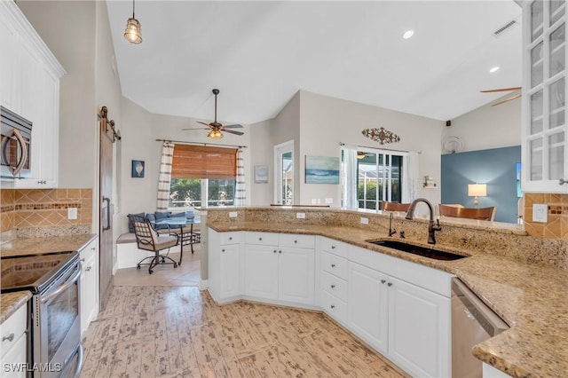 kitchen with decorative backsplash, sink, white cabinetry, hanging light fixtures, and stainless steel appliances