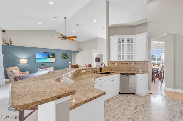 kitchen with kitchen peninsula, a breakfast bar area, stainless steel dishwasher, white cabinets, and sink