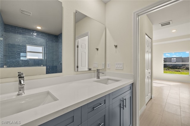 bathroom with a shower with shower door, vanity, and tile patterned flooring