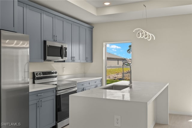 kitchen featuring decorative light fixtures, sink, a kitchen island with sink, light stone countertops, and stainless steel appliances