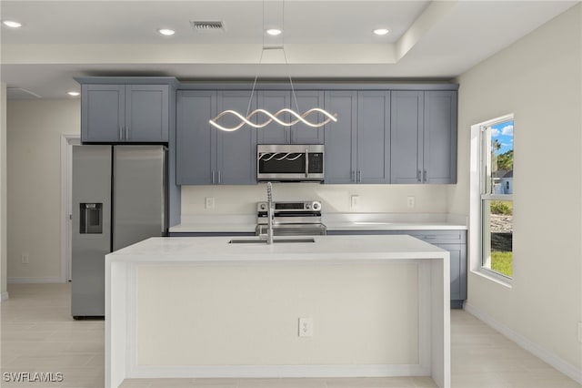 kitchen with appliances with stainless steel finishes, a center island with sink, a healthy amount of sunlight, and gray cabinetry