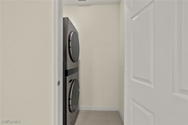 laundry area featuring light tile patterned flooring and stacked washer / dryer