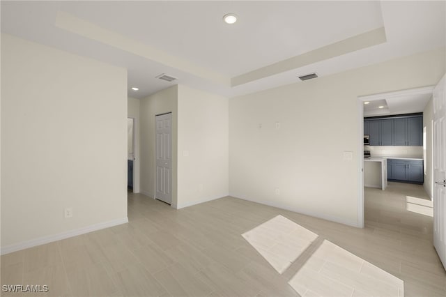 spare room featuring a raised ceiling and light tile patterned flooring