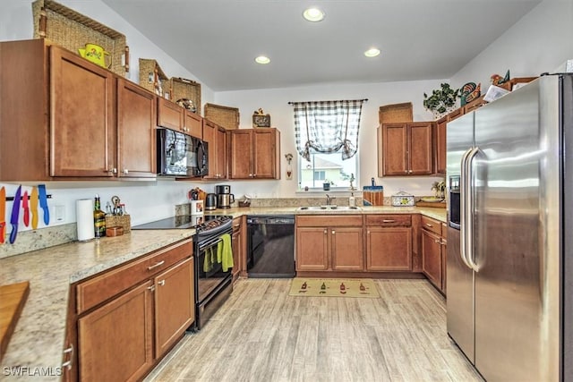 kitchen with black appliances, light stone countertops, sink, and light hardwood / wood-style floors