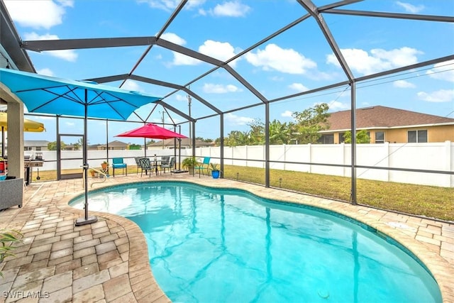 view of pool with glass enclosure and a patio area