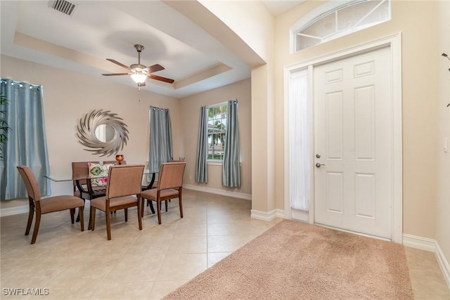 tiled entrance foyer featuring ceiling fan and a raised ceiling