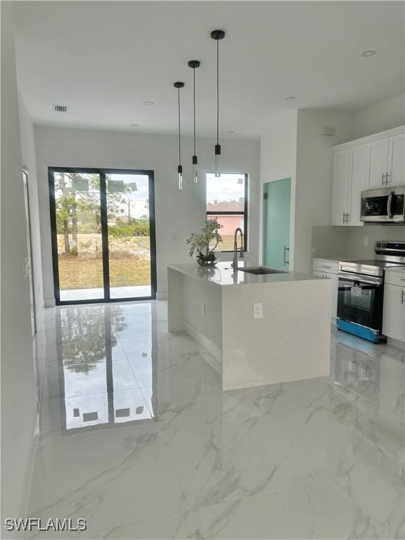 kitchen featuring a center island with sink, appliances with stainless steel finishes, pendant lighting, white cabinets, and sink