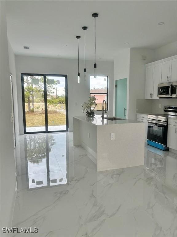 3204 20th St SW, Lehigh Acres, FL 33976 - kitchen featuring stainless steel appliances, white cabinets, decorative light fixtures, and light countertops
