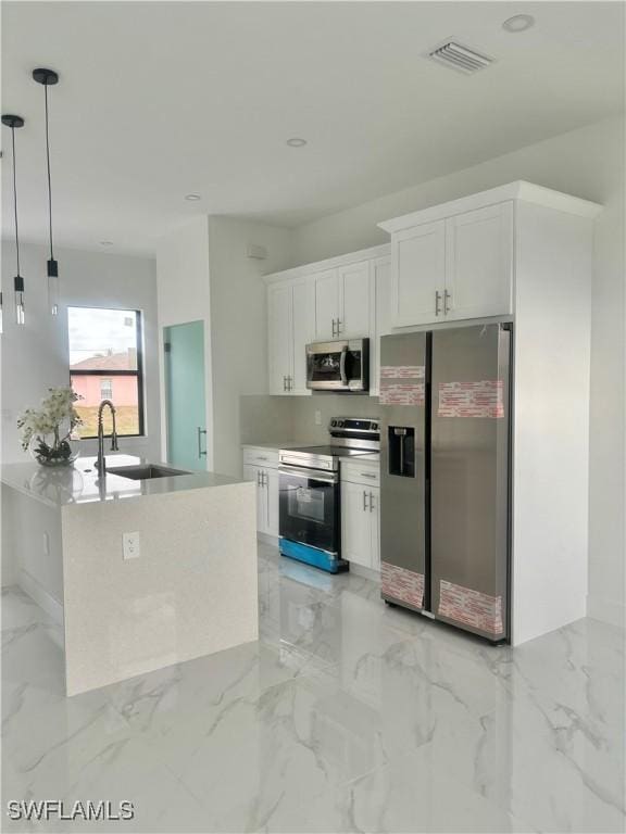 kitchen with white cabinetry, appliances with stainless steel finishes, decorative light fixtures, a kitchen island, and sink