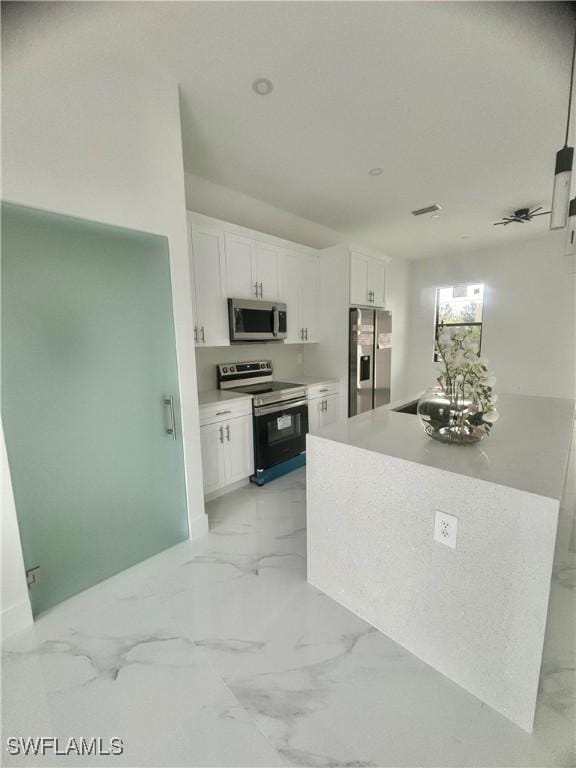 3204 20th St SW, Lehigh Acres, FL 33976 - kitchen with appliances with stainless steel finishes, white cabinets, light marble finish floors, and light countertops