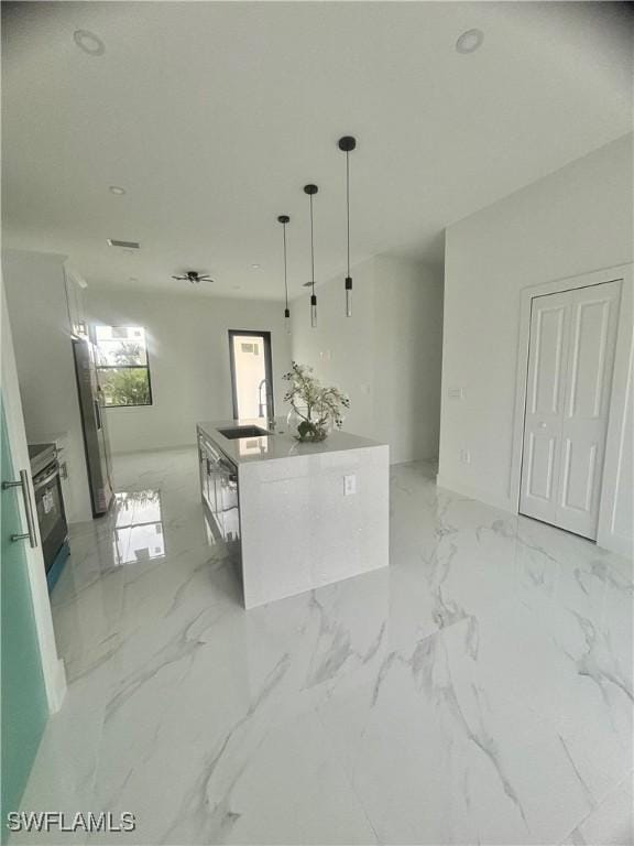 kitchen with pendant lighting, fridge, sink, white cabinetry, and an island with sink