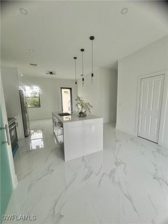 3204 20th St SW, Lehigh Acres, FL 33976 - kitchen with a center island with sink, decorative light fixtures, appliances with stainless steel finishes, light marble finish floors, and white cabinets