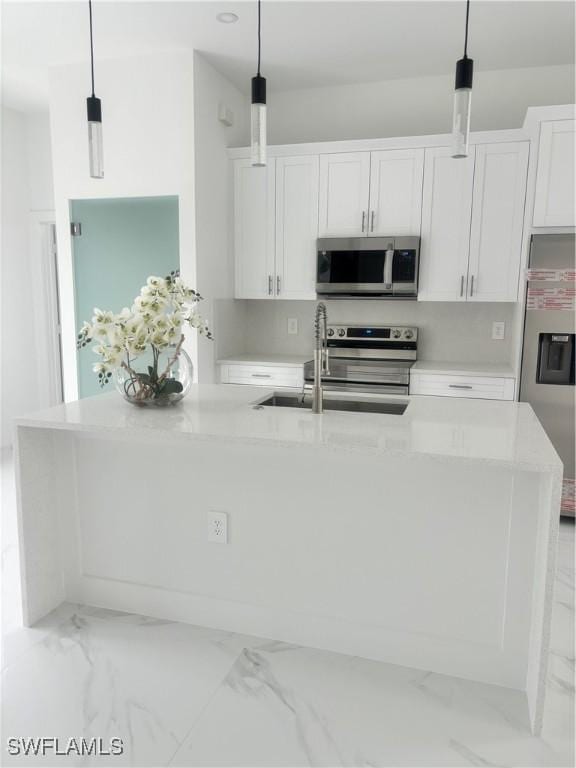 3204 20th St SW, Lehigh Acres, FL 33976 - kitchen with appliances with stainless steel finishes, light marble finish floors, white cabinetry, and pendant lighting