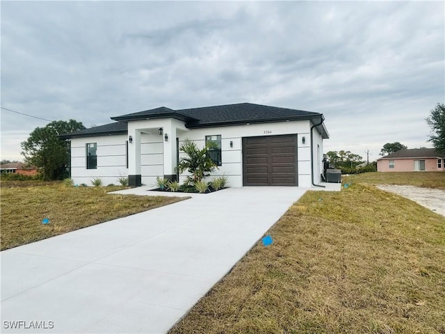 view of front of home with central AC, a garage, and a front yard