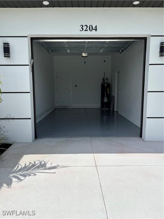 3204 20th St SW, Lehigh Acres, FL 33976 - garage featuring water heater and concrete driveway