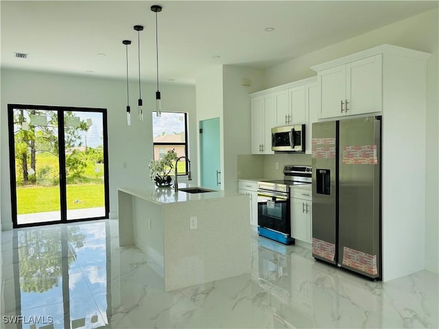 3204 20th St SW, Lehigh Acres, FL 33976 - kitchen featuring stainless steel appliances, white cabinetry, light marble finish floors, decorative light fixtures, and light countertops
