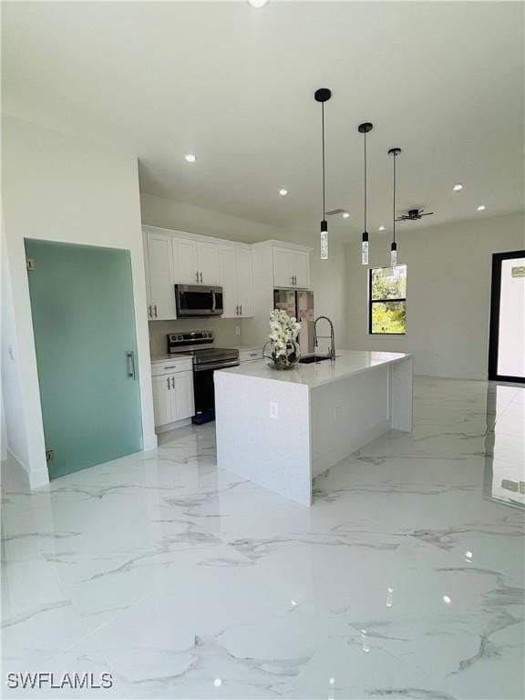 3204 20th St SW, Lehigh Acres, FL 33976 - kitchen featuring appliances with stainless steel finishes, white cabinets, hanging light fixtures, an island with sink, and recessed lighting