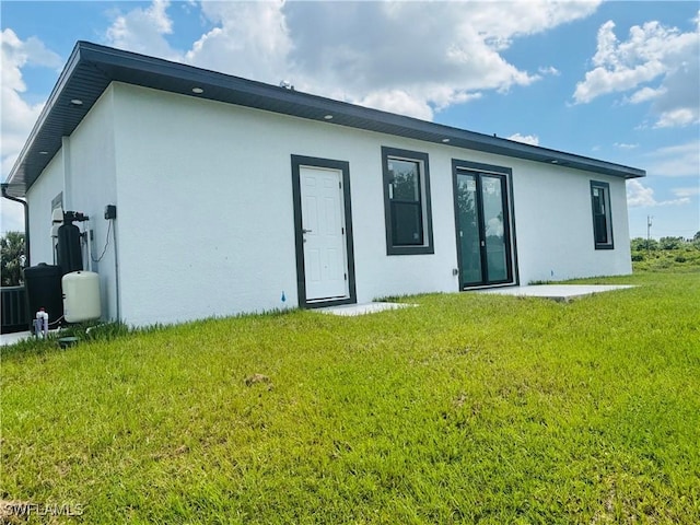 3204 20th St SW, Lehigh Acres, FL 33976 - back of house with stucco siding and a yard