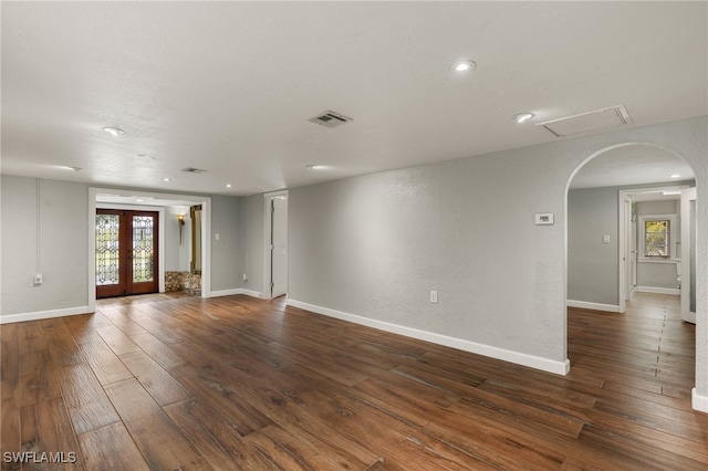 empty room with french doors, plenty of natural light, and dark hardwood / wood-style floors