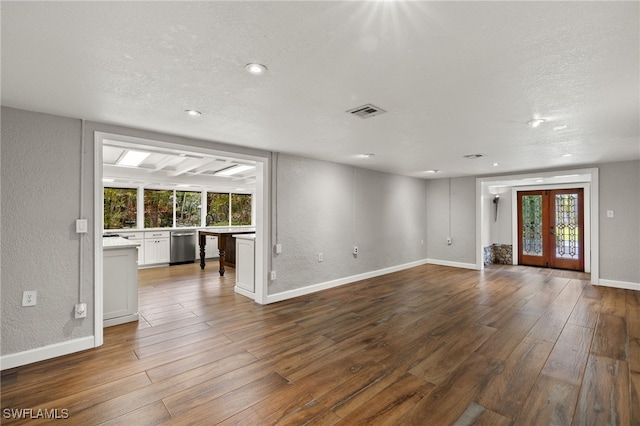 unfurnished living room featuring a textured ceiling, wood-type flooring, and french doors