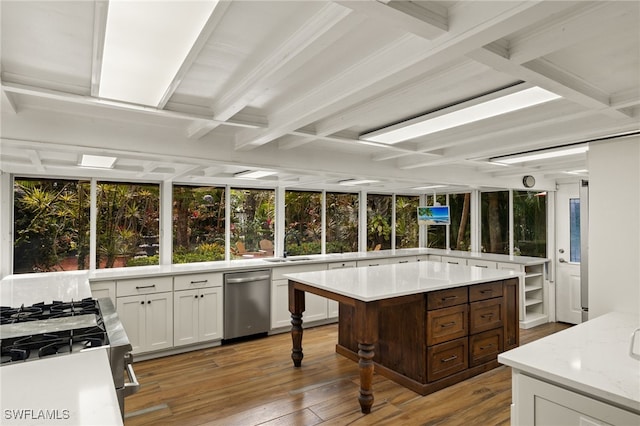 kitchen with light stone countertops, dark brown cabinetry, a center island, stainless steel appliances, and light hardwood / wood-style floors