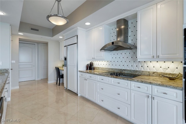 kitchen with black electric cooktop, decorative light fixtures, light stone countertops, wall chimney exhaust hood, and white cabinets