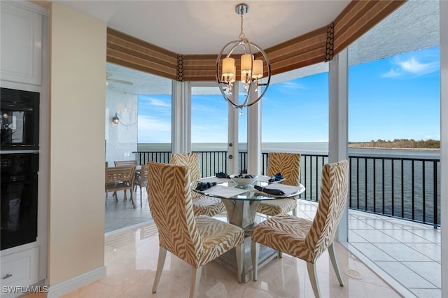 tiled dining space with a notable chandelier and a water view