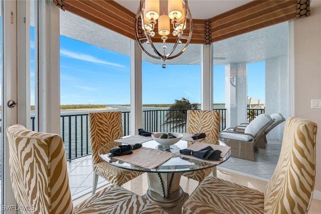 sunroom featuring a water view, plenty of natural light, and a notable chandelier