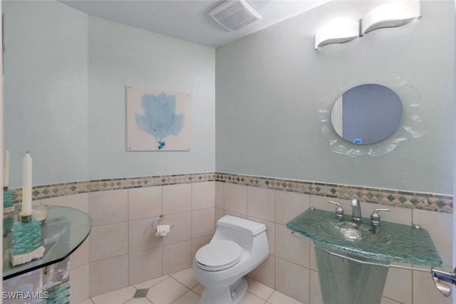 bathroom featuring toilet, tile patterned flooring, and tile walls