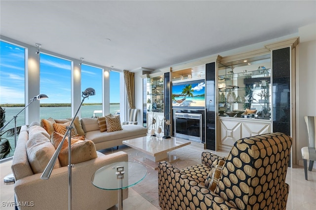 living room with floor to ceiling windows, a water view, and a fireplace