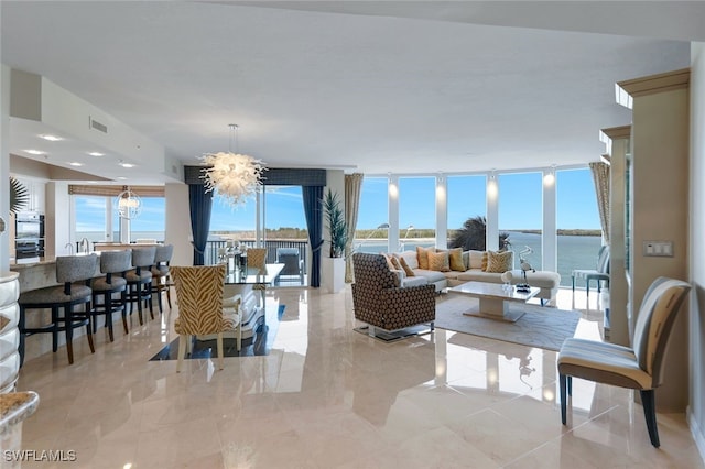 living room with floor to ceiling windows, a chandelier, and a water view