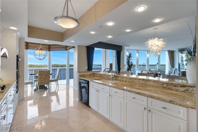 kitchen featuring black appliances, a water view, hanging light fixtures, and sink