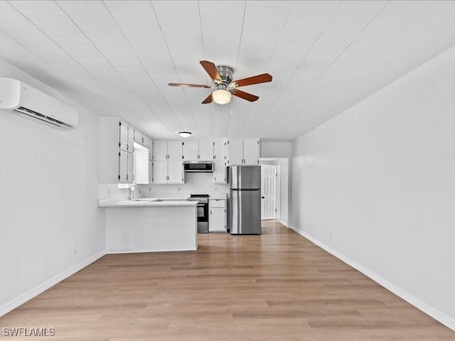 kitchen featuring white cabinets, appliances with stainless steel finishes, kitchen peninsula, a wall unit AC, and range hood