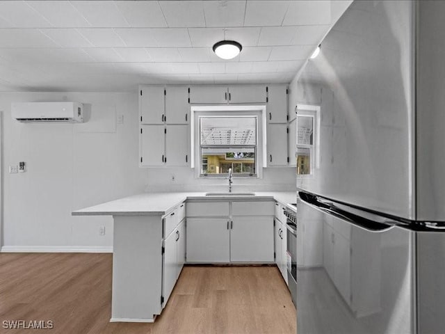 kitchen featuring light hardwood / wood-style floors, stainless steel fridge, a wall mounted air conditioner, white cabinets, and sink