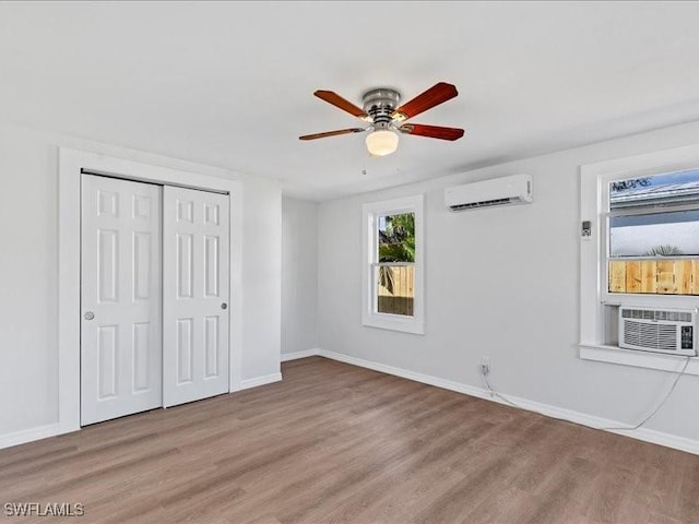 unfurnished bedroom with ceiling fan, light hardwood / wood-style floors, a wall unit AC, cooling unit, and a closet