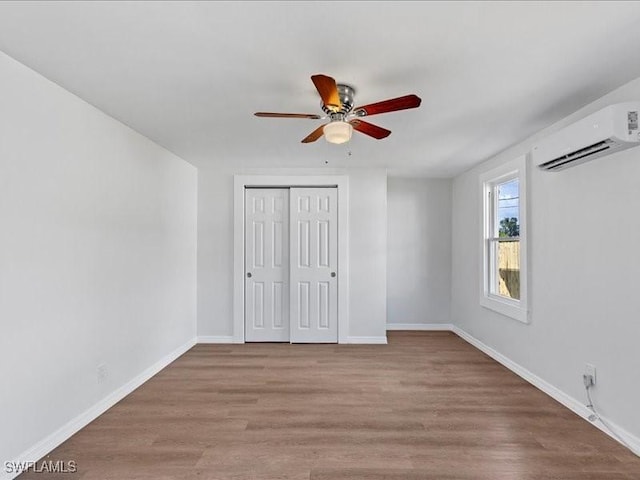 unfurnished bedroom with ceiling fan, light hardwood / wood-style floors, a closet, and a wall mounted air conditioner