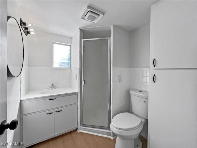 bathroom with a shower with shower door, vanity, tile walls, and hardwood / wood-style flooring