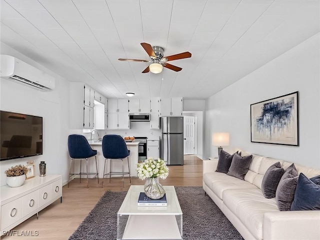 living room with light hardwood / wood-style floors, sink, ceiling fan, and a wall mounted air conditioner