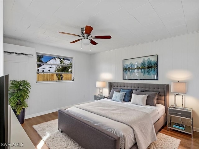 bedroom featuring ceiling fan, a wall mounted AC, and hardwood / wood-style floors