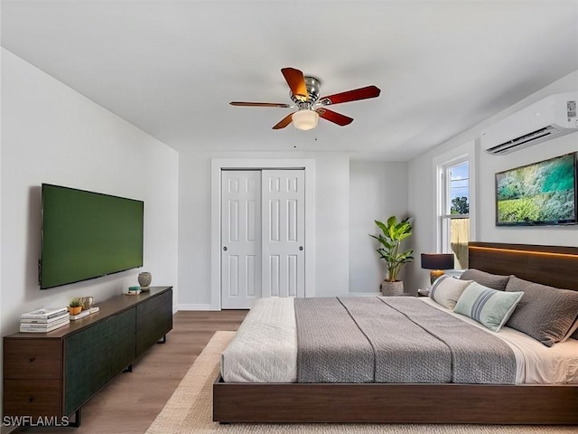 bedroom featuring ceiling fan, light hardwood / wood-style floors, and a wall unit AC