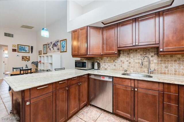 kitchen with kitchen peninsula, sink, decorative light fixtures, tasteful backsplash, and stainless steel appliances