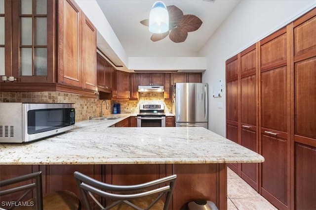 kitchen with kitchen peninsula, sink, tasteful backsplash, a breakfast bar, and stainless steel appliances