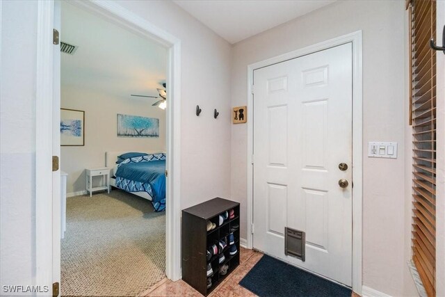 carpeted foyer entrance with ceiling fan