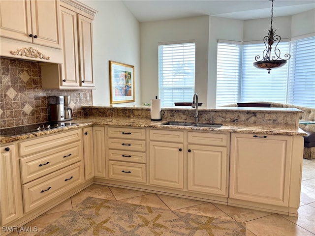 kitchen featuring decorative backsplash, a sink, black electric cooktop, and light stone countertops